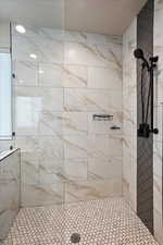 Full bath featuring a textured ceiling and tiled shower