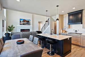 Kitchen with light wood-style floors, stainless steel gas stovetop, light countertops, and decorative backsplash