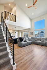 Living area featuring recessed lighting, stairway, a ceiling fan, wood finished floors, and high vaulted ceiling