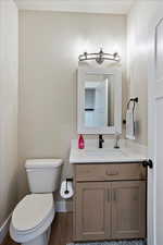 Half bath with wood finished floors, vanity, toilet, and baseboards