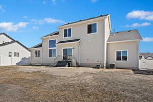 Rear view of house with fence, cooling unit, and stucco siding