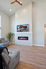 Living room featuring lofted ceiling, a fireplace, baseboards, and wood finished floors