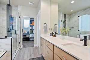 Full bath featuring double vanity, a stall shower, visible vents, wood finish floors, and a sink