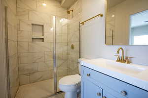 Bathroom featuring tiled shower, vanity, and toilet