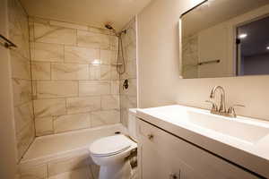 Full bath featuring toilet, a tile shower, and vanity