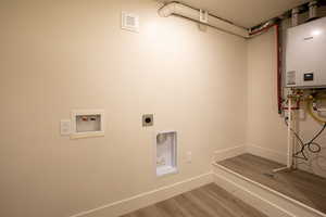 Laundry room featuring laundry area, wood finished floors, hookup for a washing machine, tankless water heater, and hookup for an electric dryer