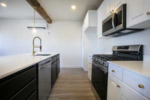 Kitchen with stainless steel appliances, a wall unit AC, a sink, and light countertops