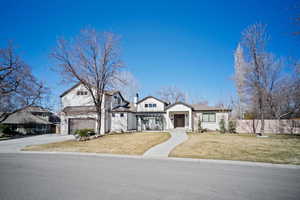 View of front of home featuring driveway, a front yard, fence, and a chimney