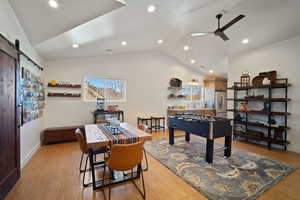 Playroom with light wood-style floors, a barn door, vaulted ceiling, and ceiling fan