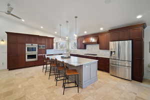 Kitchen featuring a center island, custom exhaust hood, stainless steel appliances, lofted ceiling, and tasteful backsplash