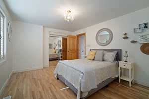 Bedroom featuring a notable chandelier, a closet, visible vents, light wood-type flooring, and baseboards