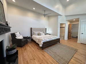 Bedroom featuring baseboards, recessed lighting, a fireplace, a high ceiling, and light wood finished floors