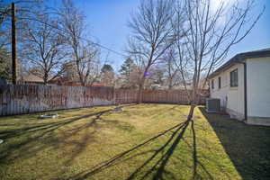 View of yard with cooling unit and a fenced backyard