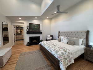 Bedroom featuring recessed lighting, a walk in closet, wood finished floors, a large fireplace, and high vaulted ceiling