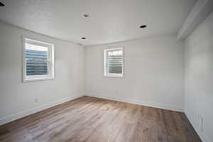 Unfurnished room featuring plenty of natural light, wood finished floors, visible vents, and baseboards