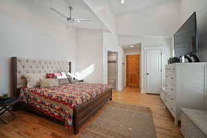 Bedroom with recessed lighting, light wood-style floors, a ceiling fan, ensuite bath, and high vaulted ceiling