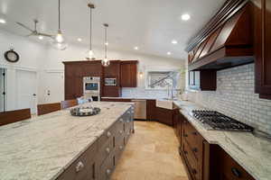 Kitchen with premium range hood, light stone counters, stainless steel appliances, and a sink