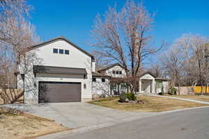 View of front of home with an attached garage, fence, driveway, and a front lawn