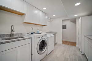 Laundry area with washing machine and clothes dryer, recessed lighting, a sink, light wood-type flooring, and electric panel