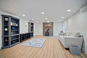 Living area featuring baseboards, wood finished floors, a wood stove, and recessed lighting