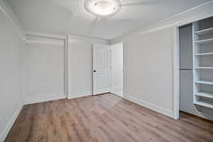 Unfurnished bedroom featuring a closet, a textured ceiling, baseboards, and wood finished floors