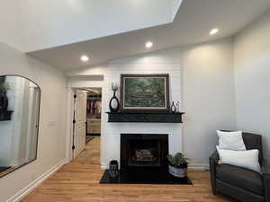 Living room with light wood-style floors, baseboards, a large fireplace, and recessed lighting