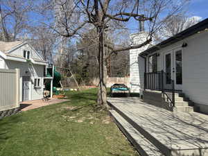View of yard featuring french doors, fence, a playground, and driveway