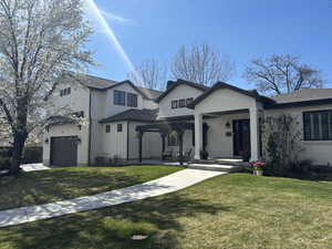 View of front of house with a garage, covered porch, a front lawn, and brick siding