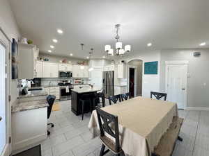 Dining room featuring a toaster, baseboards, arched walkways, a notable chandelier, and recessed lighting