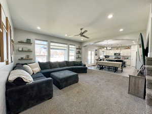 Living area featuring arched walkways, light colored carpet, ceiling fan with notable chandelier, a textured ceiling, and recessed lighting