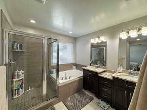 Bathroom with tile patterned floors, a garden tub, a textured ceiling, vanity, and a shower stall