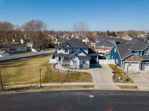 Traditional-style home with fence, driveway, stone siding, a residential view, and a front yard