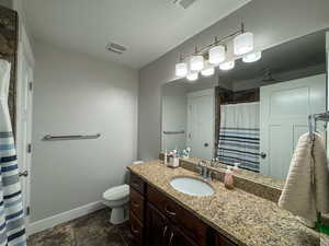 Full bathroom featuring visible vents, baseboards, a shower with shower curtain, toilet, and vanity