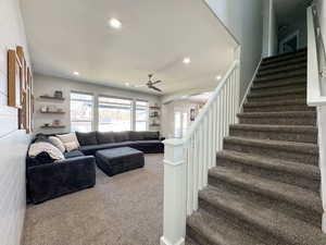 Carpeted living room with arched walkways, ceiling fan, stairs, a textured ceiling, and recessed lighting