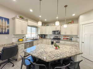 Kitchen with a breakfast bar area, stainless steel appliances, backsplash, white cabinets, and a sink