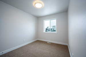 Empty room featuring dark colored carpet, visible vents, and baseboards