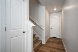 Doorway to outside featuring visible vents, stairway, baseboards, and wood finished floors