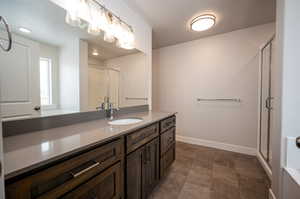 Full bathroom featuring a shower stall, baseboards, and vanity