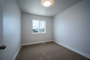 Empty room with baseboards, visible vents, and dark carpet