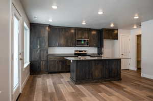 Kitchen featuring stainless steel appliances, a sink, dark brown cabinets, and wood finished floors