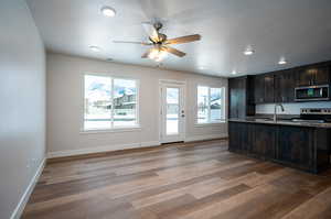 Kitchen with dark brown cabinetry, baseboards, appliances with stainless steel finishes, wood finished floors, and a sink