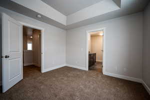 Unfurnished bedroom featuring dark colored carpet and baseboards