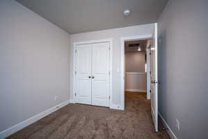 Unfurnished bedroom featuring dark colored carpet, a closet, visible vents, and baseboards