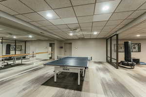 Game room with baseboards, wood finished floors, a drop ceiling, and recessed lighting