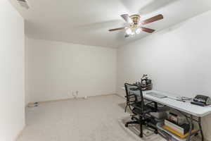 Home office featuring a ceiling fan, light carpet, visible vents, and baseboards