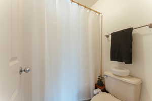 Full bath featuring toilet and a shower with curtain