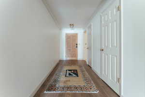 Hall featuring baseboards, ornamental molding, and wood finished floors