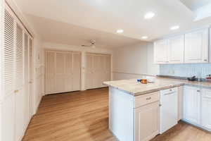 Kitchen featuring white cabinets, dishwasher, a peninsula, light wood-type flooring, and recessed lighting