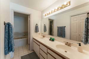 Full bath with a tub to relax in, tile patterned flooring, a sink, and double vanity