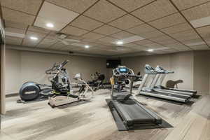 Gym featuring a paneled ceiling, baseboards, and recessed lighting